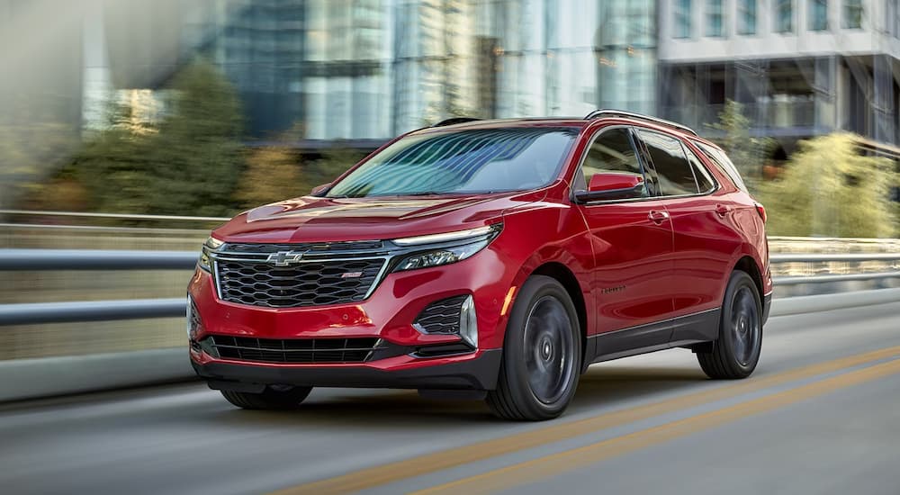 A red 2023 Chevy Equinox RS is shown driving through a city.