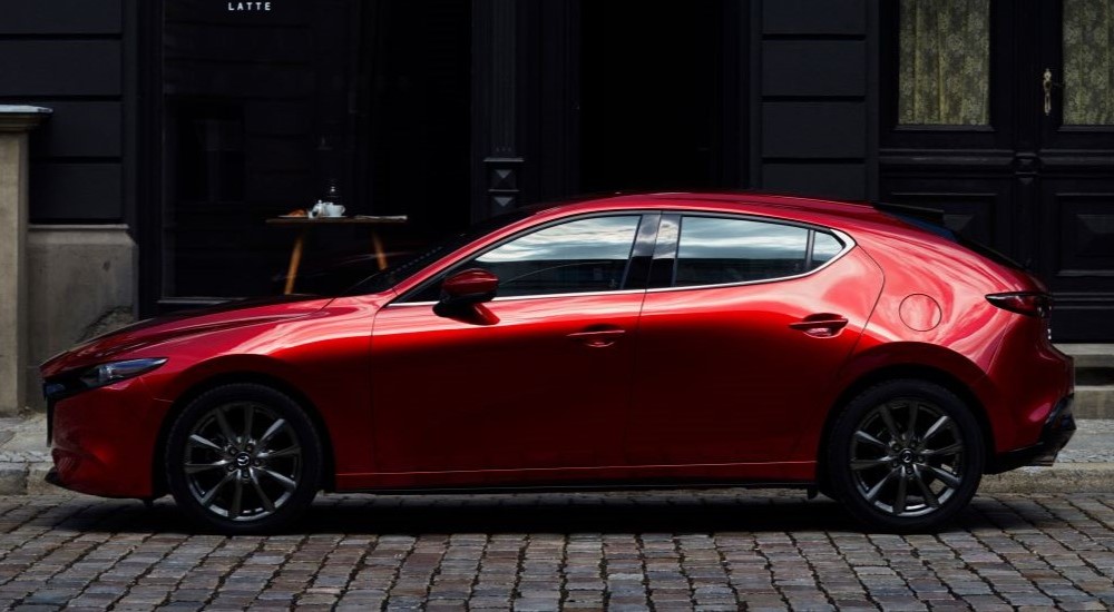 A red 2023 Mazda 3 is shown parked on a street.