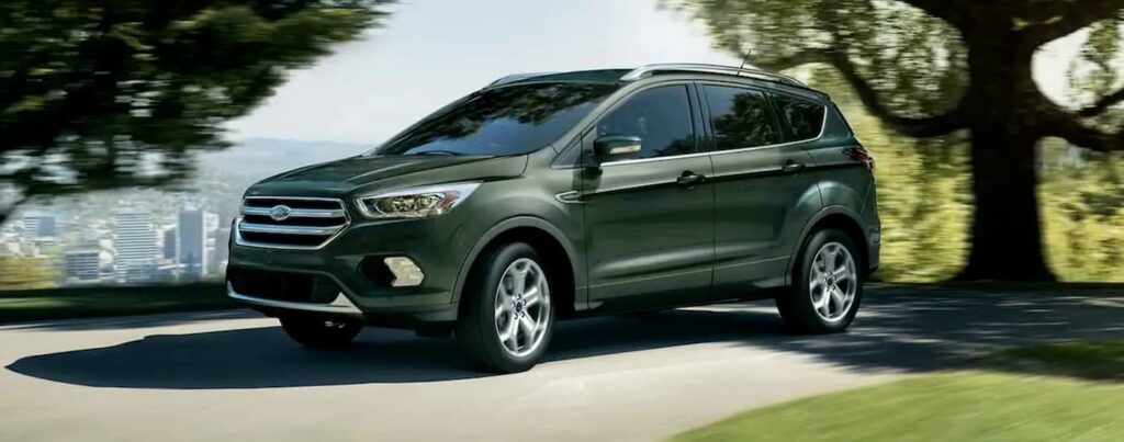 A green 2019 Ford Escape for sale is shown driving on a road.