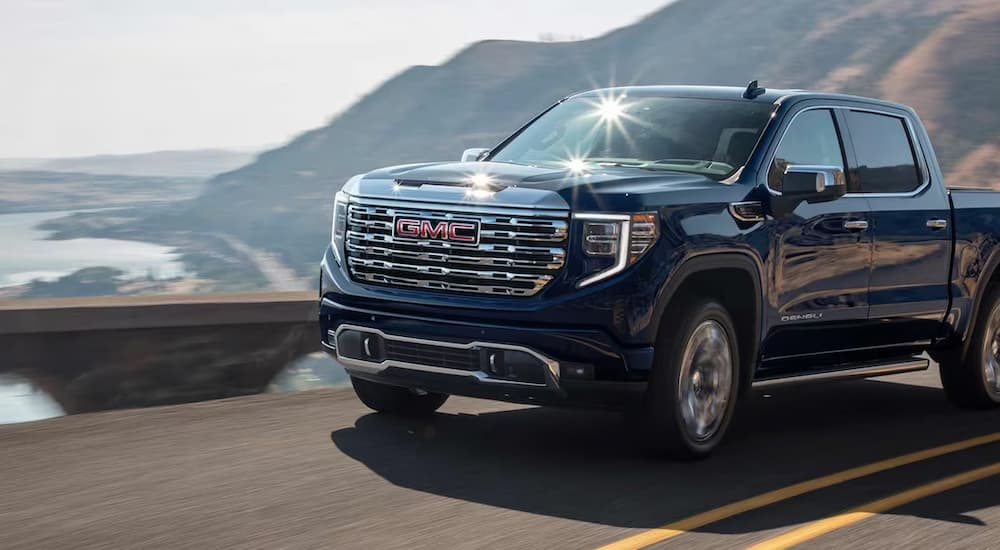 A blue 2023 Sierra 1500 Denali equipped with Super Cruise from a GMC dealer near me is shown traveling down a highway.