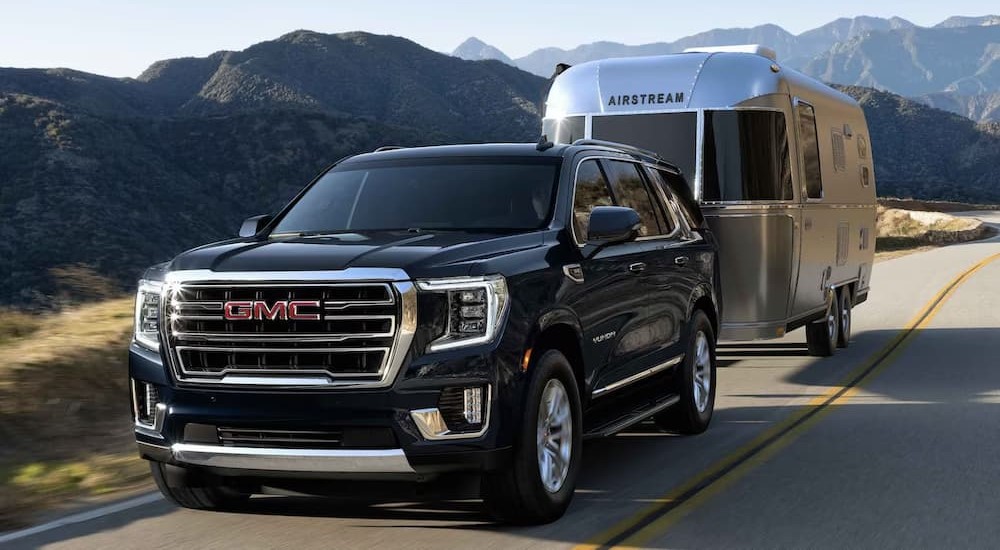 A black 2023 GMC Yukon Denali Ultimate is shown towing an Airstream.