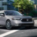 A gray 2023 Honda Accord for sale is shown being test driven in a city.