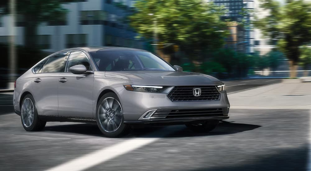 A gray 2023 Honda Accord for sale is shown being test driven in a city.