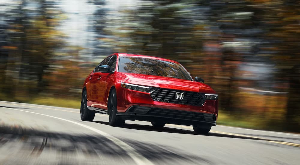 A red 2023 Honda Accord is shown driving on a road.