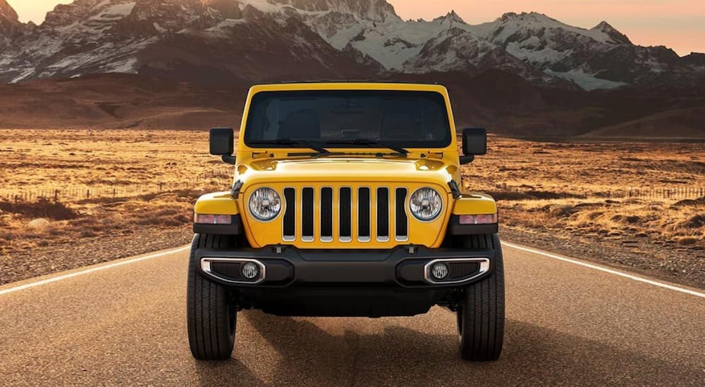 A yellow 2021 Jeep Wrangler is shown driving on a road.