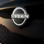 The illuminated Nissan emblem is shown on a 2023 Nissan Ariya at a Nissan dealer.