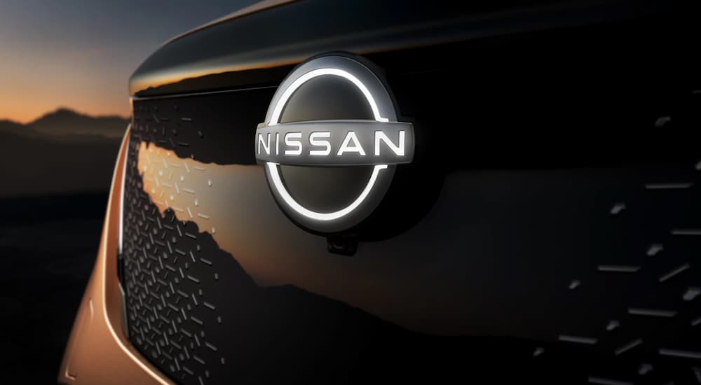 The illuminated Nissan emblem is shown on a 2023 Nissan Ariya at a Nissan dealer.