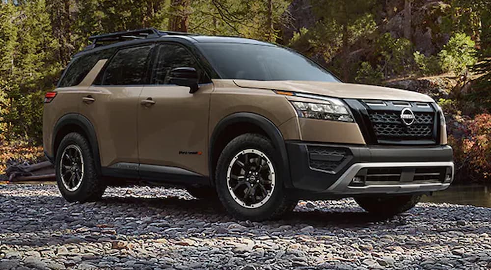 A brown 2023 Nissan Pathfinder Rock Creek is shown parked on a forest trail.