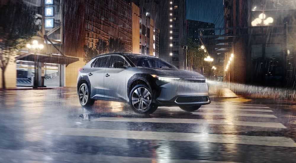 A silver and black 2023 Toyota bZ4X is shown driving on a wet road.