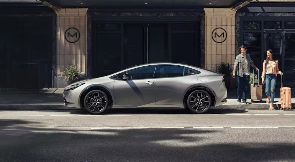 A silver 2023 Toyota Prius is shown parked near a motel.