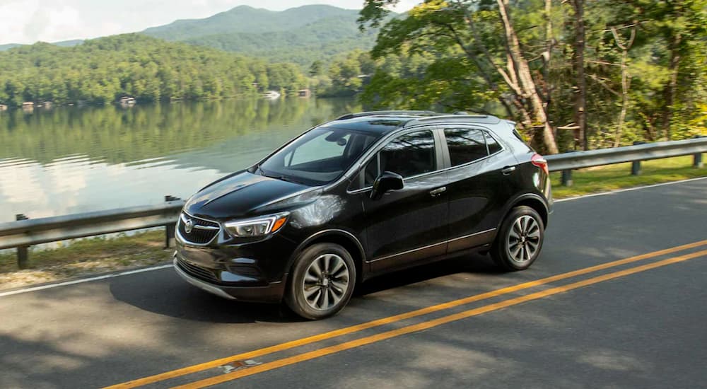 A black 2021 Buick Encore is shown driving near a lake.