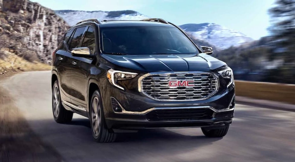 A black 2021 GMC Terrain is shown driving on a road.