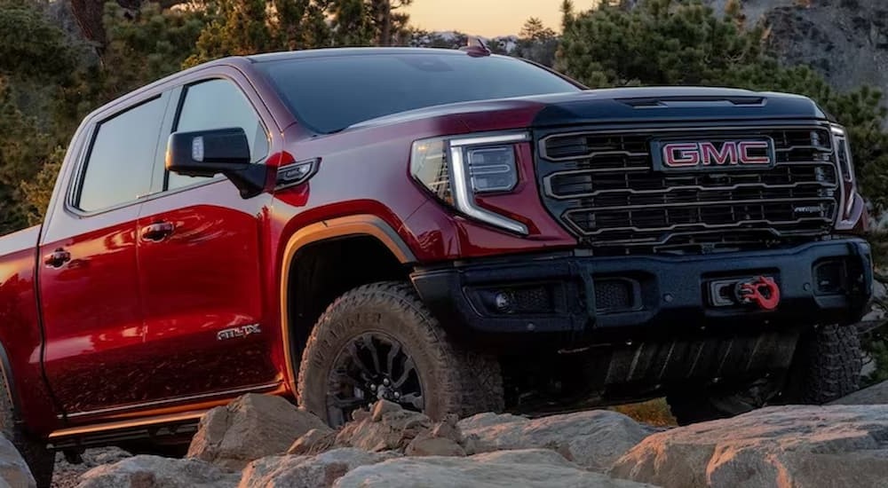 A red 2023 GMC Sierra 1500 AT4X is shown parked on boulders.