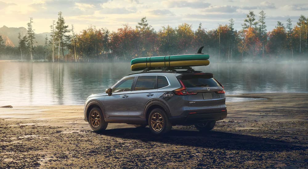 A blue 2023 Honda CR-V is shown parked on the sand near a lake.