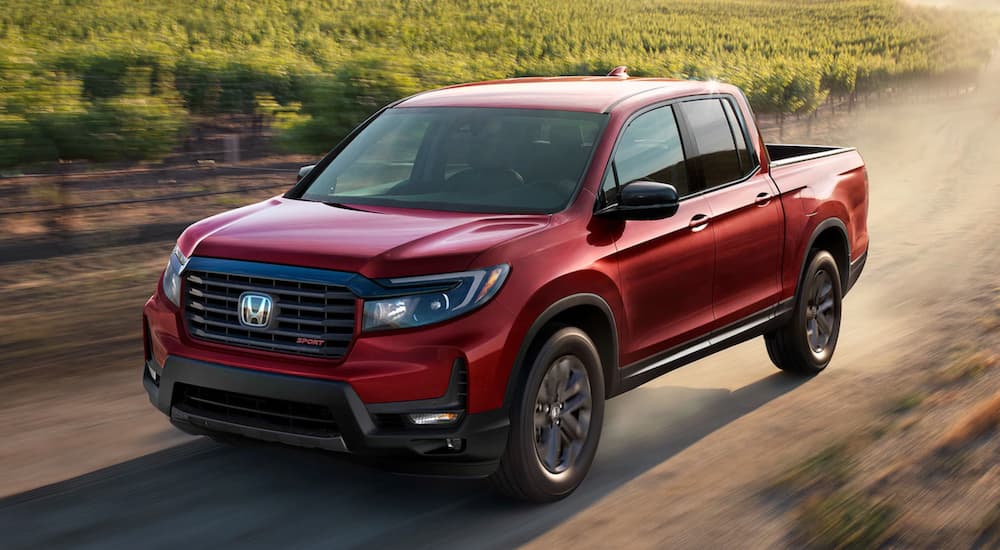 A red 2021 Honda Ridgeline is shown from the front at an angle after leaving a dealer that has a used Honda Ridgeline for sale.