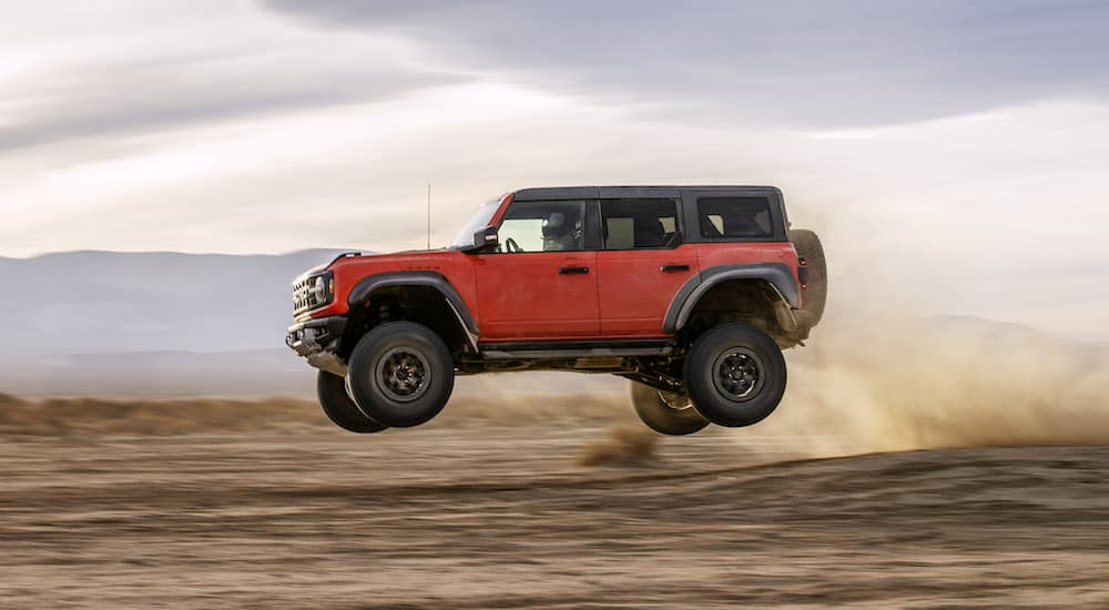 A red 2022 Ford Bronco Raptor is shown from the side while airborne. 
