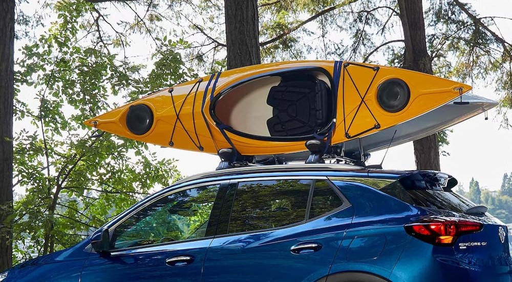 A blue 2023 Buick Encore GX is shown with two kayaks on the roof rack.