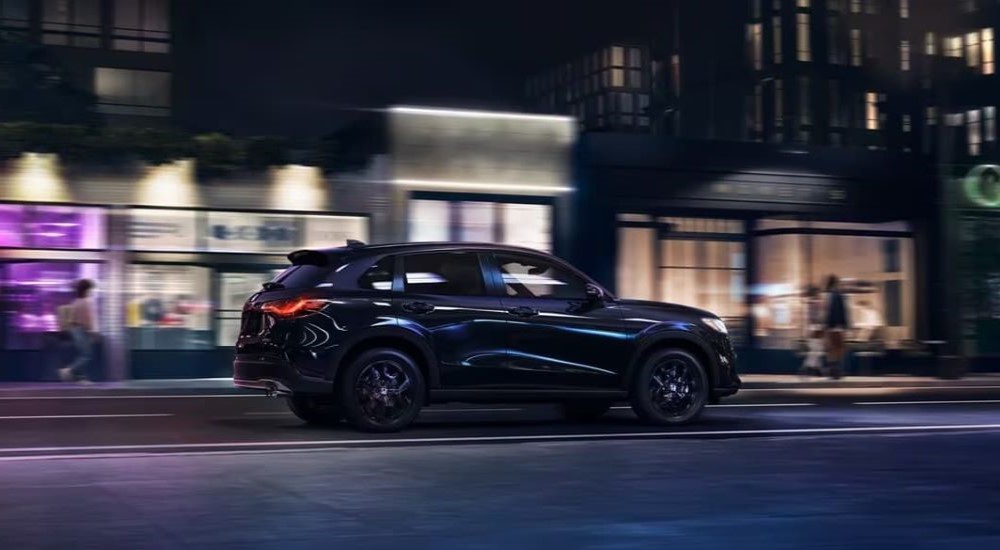 A black 2023 Honda HR-V is shown driving on a city street.