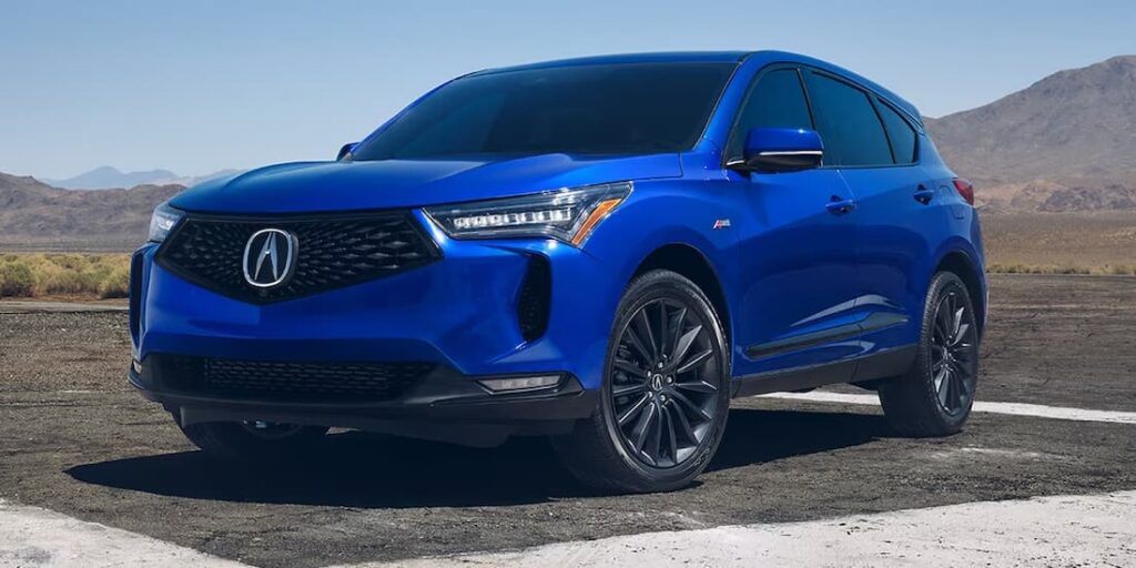 A blue 2023 Acura RDX A-Spec is shown parked near mountains.