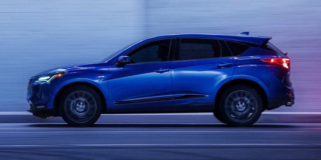 A blue 2023 Acura RDX is shown driving on a street.