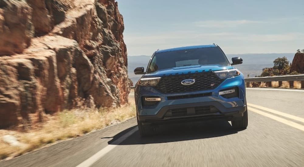 A blue 2023 Ford Explorer ST is shown driving on a highway.
