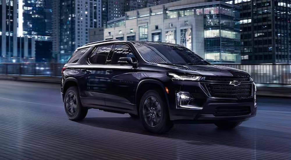 A black 2023 Chevy Traverse Midnight Edition is shown driving on a road after winning a 2023 Chevy Traverse vs 2023 Ford Explorer comparison.