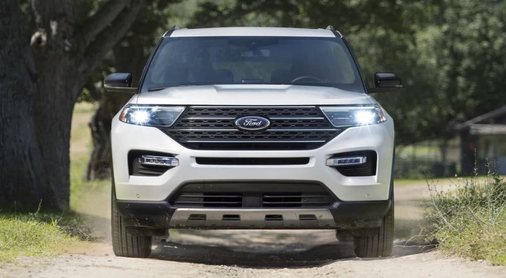 A white 2023 Ford Explorer is shown driving on a dirt road.