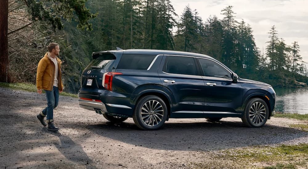 A blue 2023 Hyundai Palisade is shown parked near a lake.