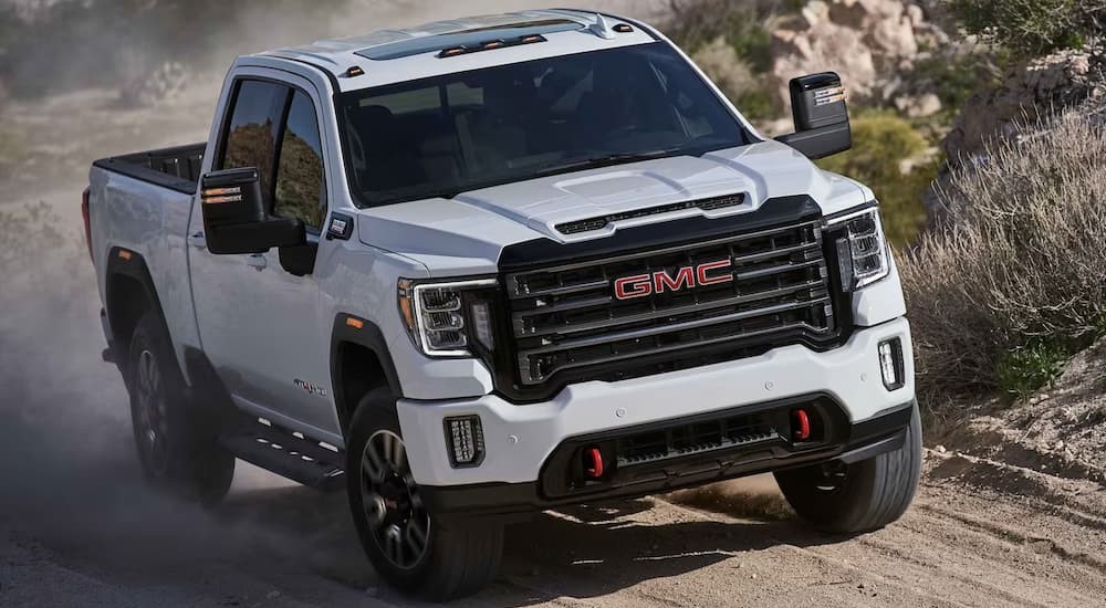 A white 2023 GMC Sierra 2500 HD AT4 is shown driving off-road.