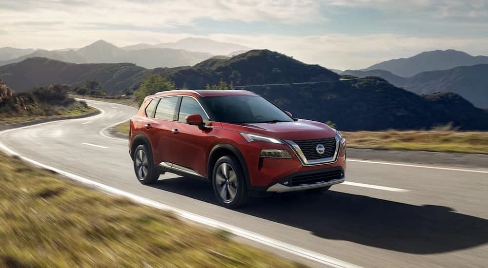 A red 2023 Nissan Rogue is shown driving on a highway.