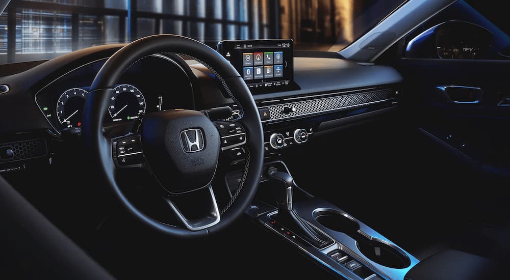 The black interior of a 2023 Honda Civic shows the steering wheel and center console.