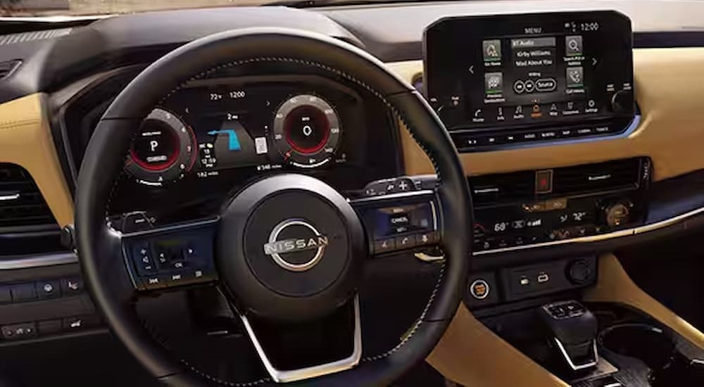 The tan and black interior and dash of a 2023 Nissan Rogue is shown.