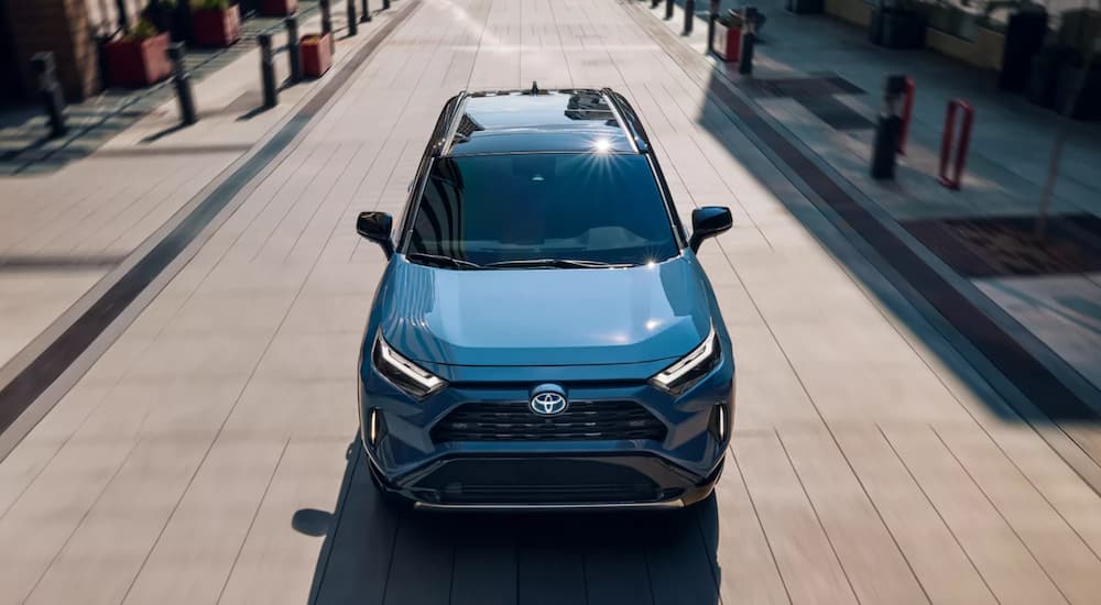 A blue 2023 Toyota RAV4 XSE Hybrid is shown driving on a road.