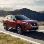 A red 2023 Nissan Rogue is shown driving after winning a 2023 Nissan Rogue vs 2023 Toyota RAV4 comparison.