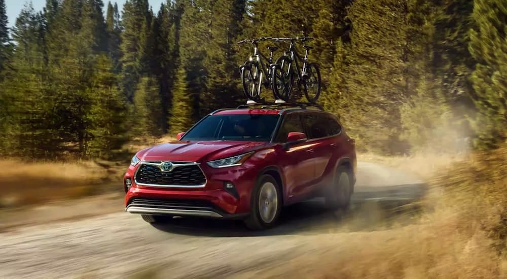 A red 2023 Toyota Highlander Hybrid is shown driving off-road.