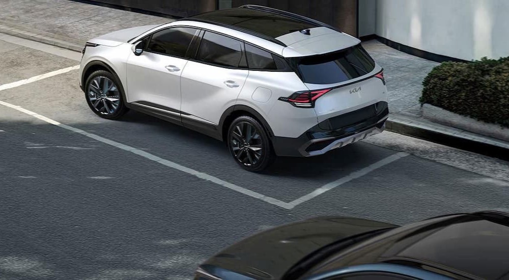 A white 2023 Kia Sportage Hybrid is shown parked on a street.