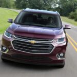 A purple 2018 Chevy Traverse for sale is shown driving on an open road.