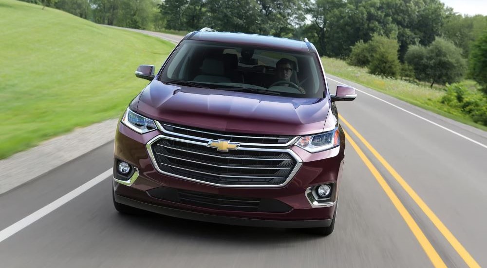 A purple 2018 Chevy Traverse for sale is shown driving on an open road.