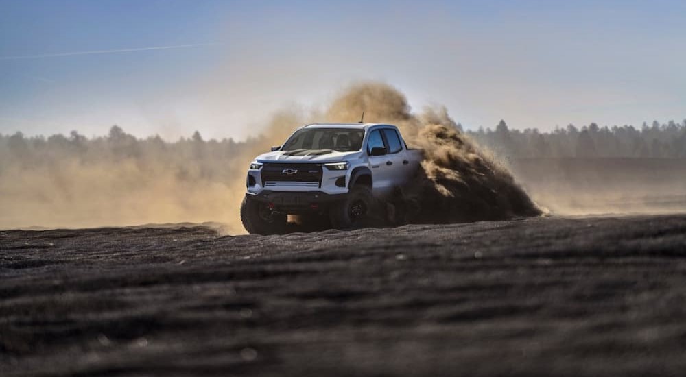 A white 2024 Chevy Colorado ZR2 Bison is shown off-roading after visiting a Chevy dealer.