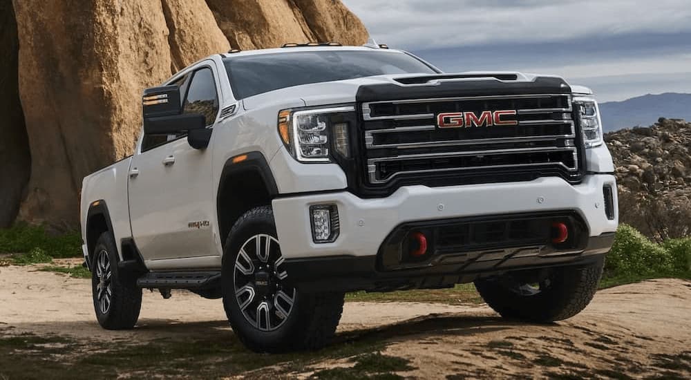 A white 2023 GMC Sierra HD AT4 is shown parked on dirt.