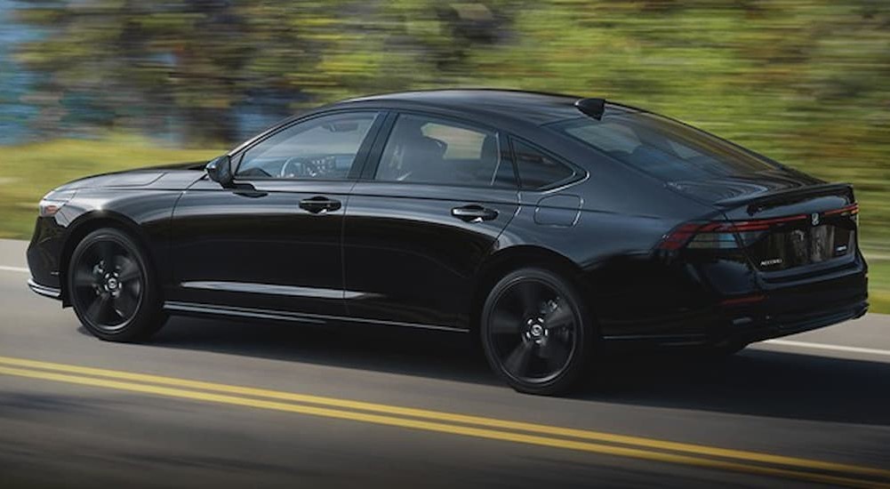 A black 2023 Honda Hybrid for sale is shown driving on a highway.