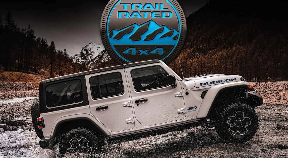 A white 2023 Jeep Wrangler Rubicon 4xe hybrid is shown off-roading after visiting a Jeep 4xe hybrid for sale.