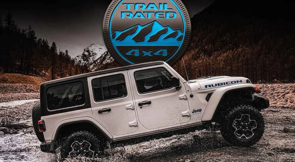 A white 2023 Jeep Wrangler Rubicon 4xe Hybrid is shown off-roading.