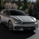 A silver 2023 Kia EV6 is shown driving on a highway.