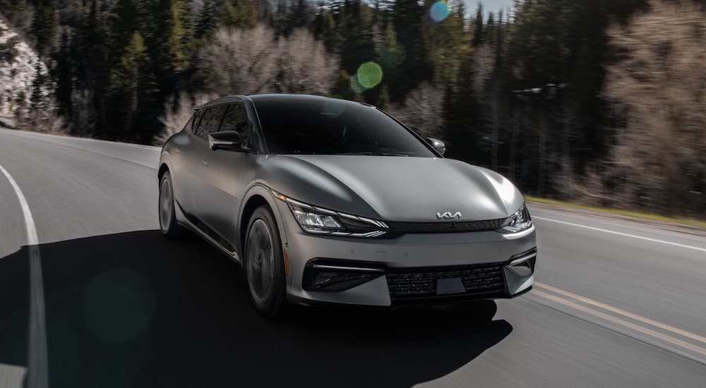 A silver 2023 Kia EV6 is shown driving on a highway.