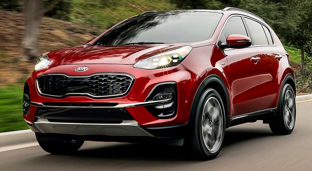 A red 2020 Kia Sportage for sale is shown driving on a road.