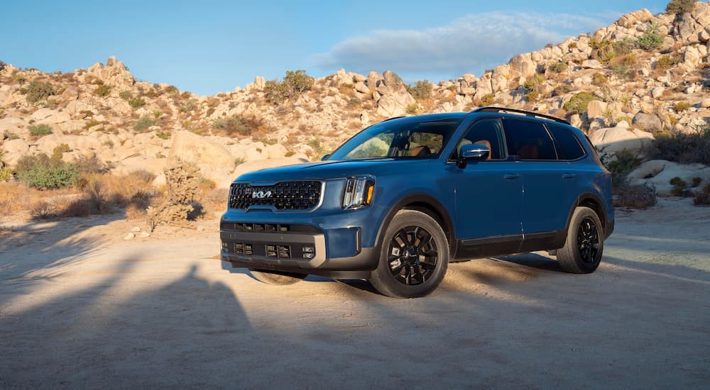 A blue 2023 Kia Telluride for sale is shown parked off-road.