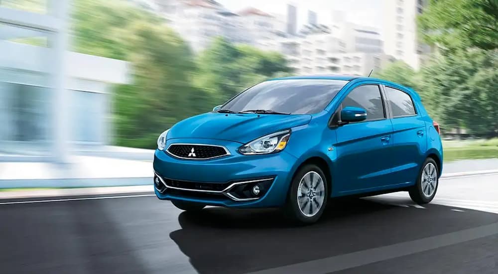 A blue 2020 Mitsubishi Mirage G4 is shown driving near a building.