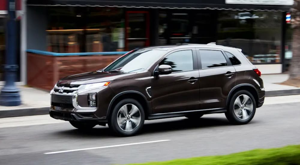 A brown 2021 Mitsubishi Outlander Sport is shown driving on a city road.