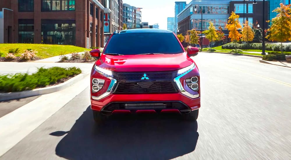 The grille of a red 2023 Mitsubishi Eclipse Cross is shown while driving on a city street.